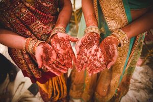 Detail shots of traditional Indian bridal henna designs on hands with gold jewelry and green fabric.