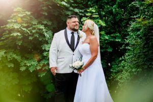 Wedding couple sharing tender moments among lush green foliage in natural outdoor setting.
