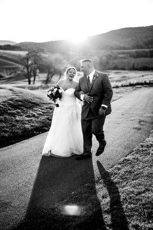 Black and white wedding photos on a hillside path at sunset.