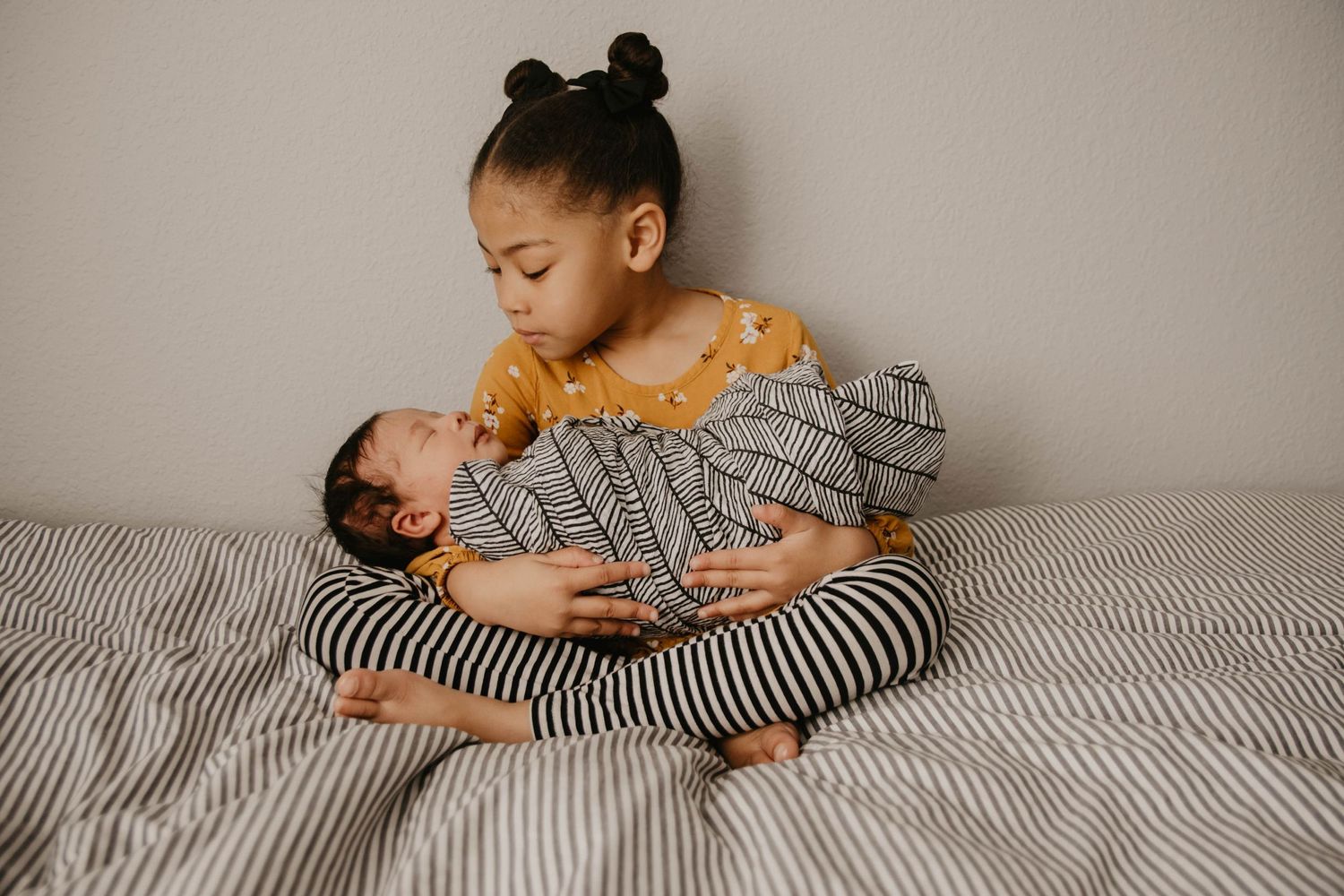 A tender moment between caregiver and baby on striped bedding.