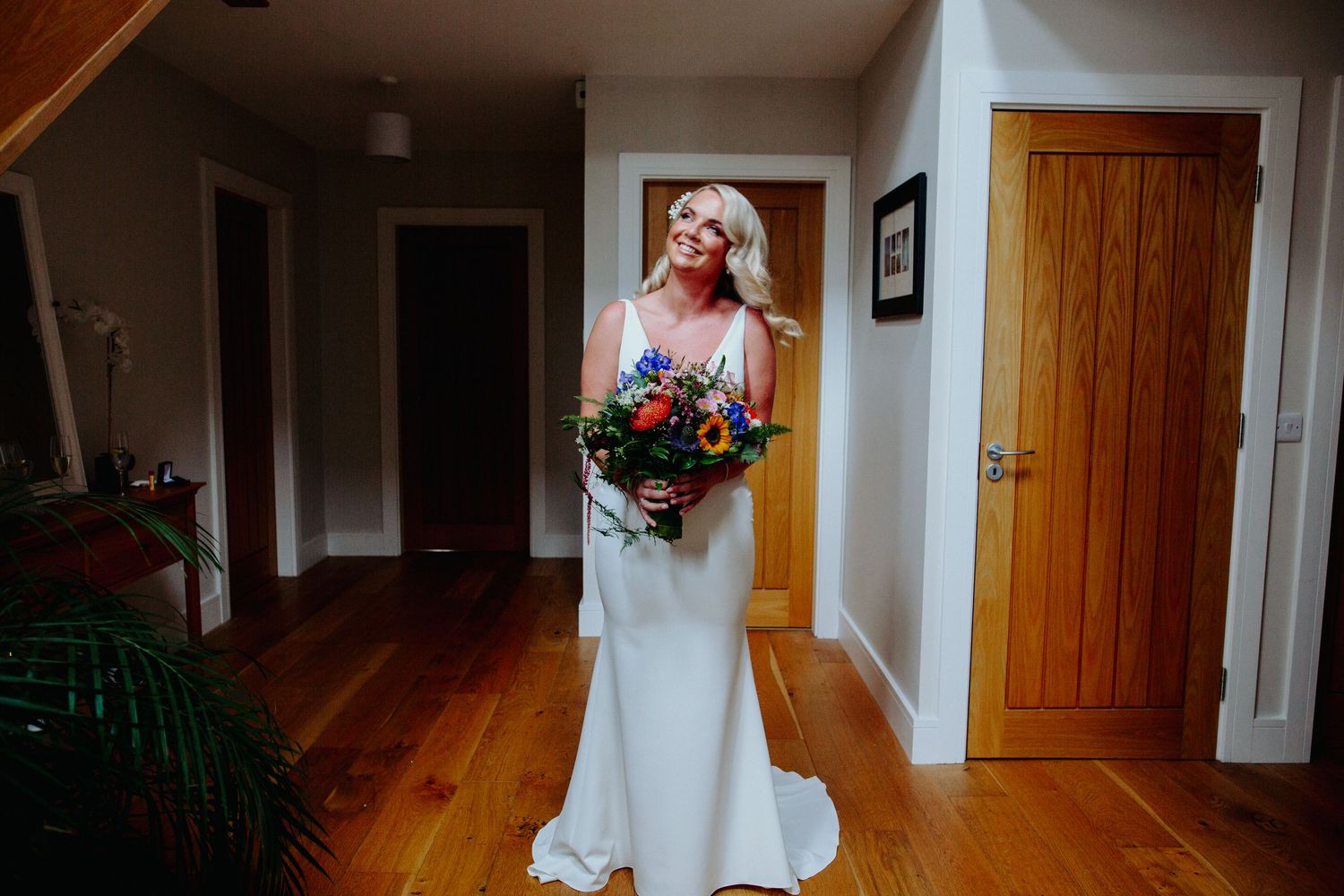An elegant bridal portrait in a sunlit hallway with wooden floors and doors.