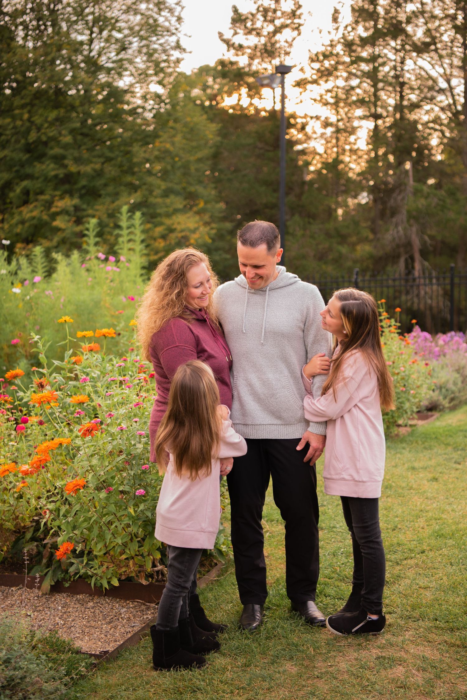 family of four standing close and looking at each other in the flower garden at hartwood acres