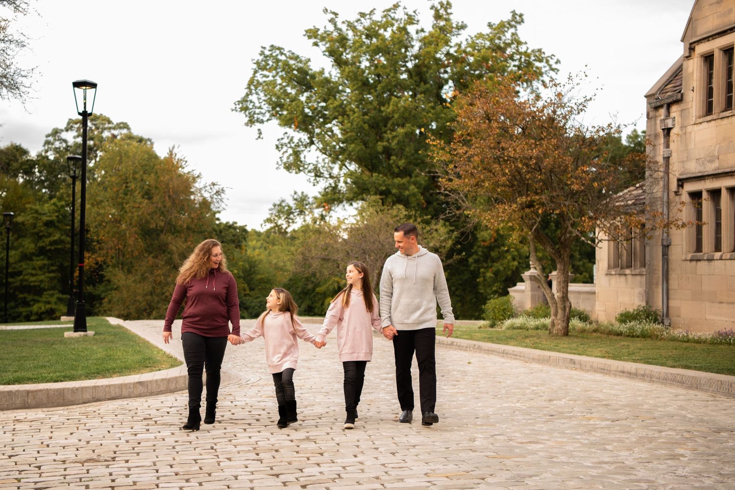 family of four holding hands and walking on cobblestone driveway in hartwood acres