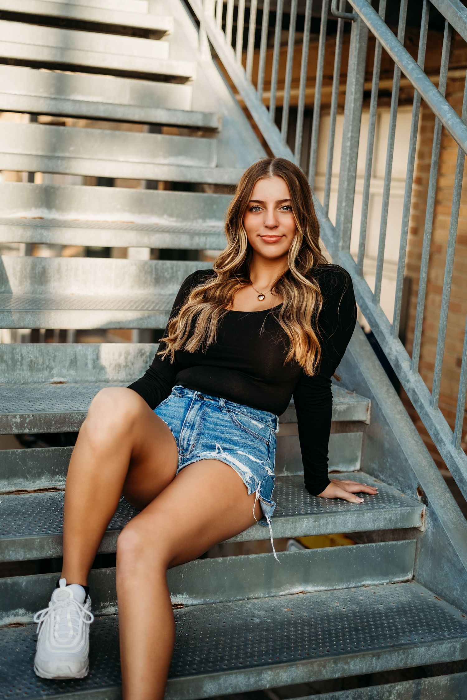 High School senior girl sits on steps outside posing for senior photography session in Kansas City, Missouri.