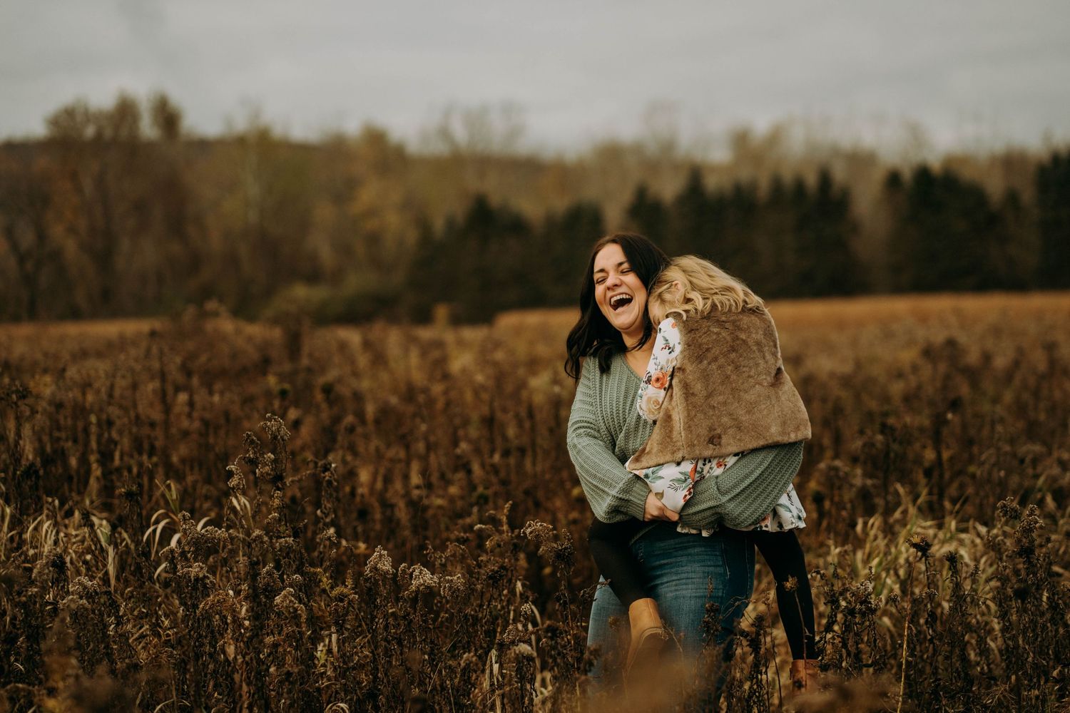 Person stands in a rustic autumn field wearing a sweater at golden hour.