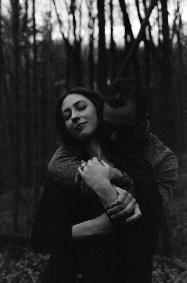 Moody forest photoshoot capturing intimate moments between a couple.