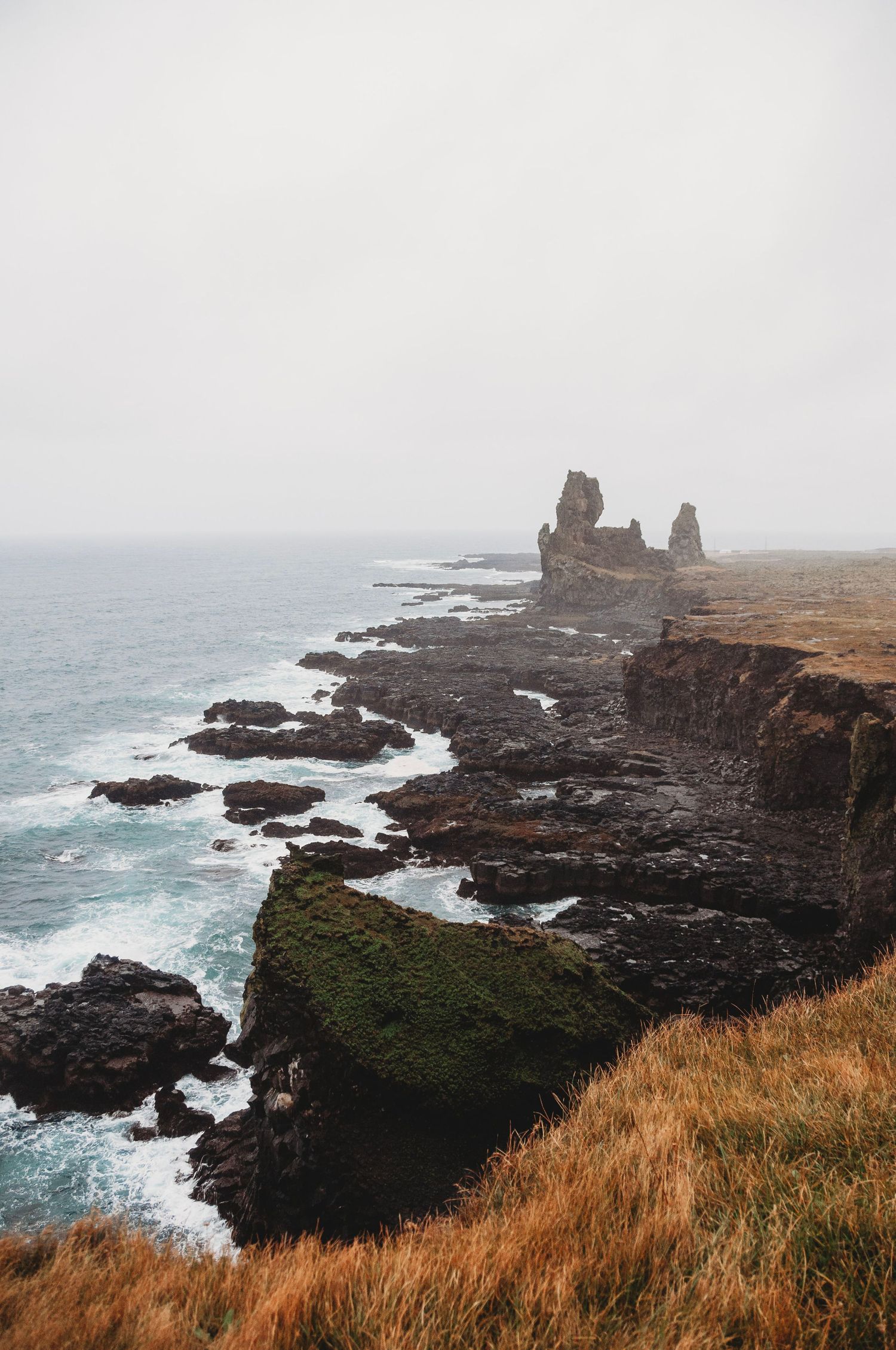 The cliffs edge on a misty foggy day by the ocean in Iceland. The landscape is very jagged.