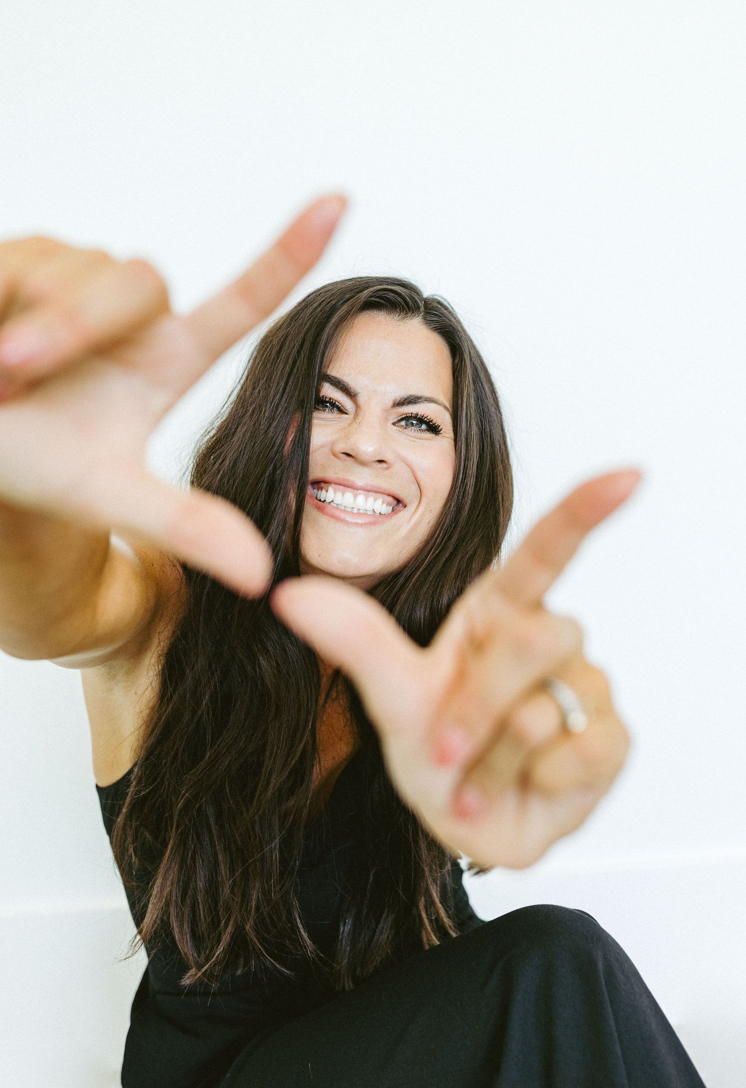 A woman smiling at the camera and holding up her fingers