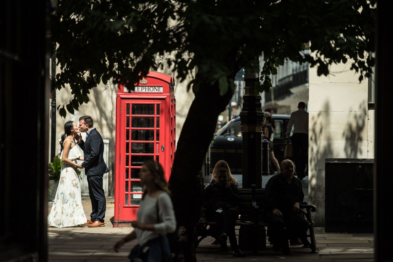 Newlyweds kiss next to a red telephone box in Shepherds Market