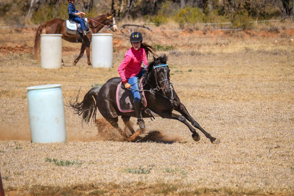 Horse and rider rounding a barrel at full gallop during a competitive event.