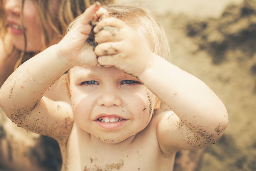 Boy holding sand in his hand at the beach photo