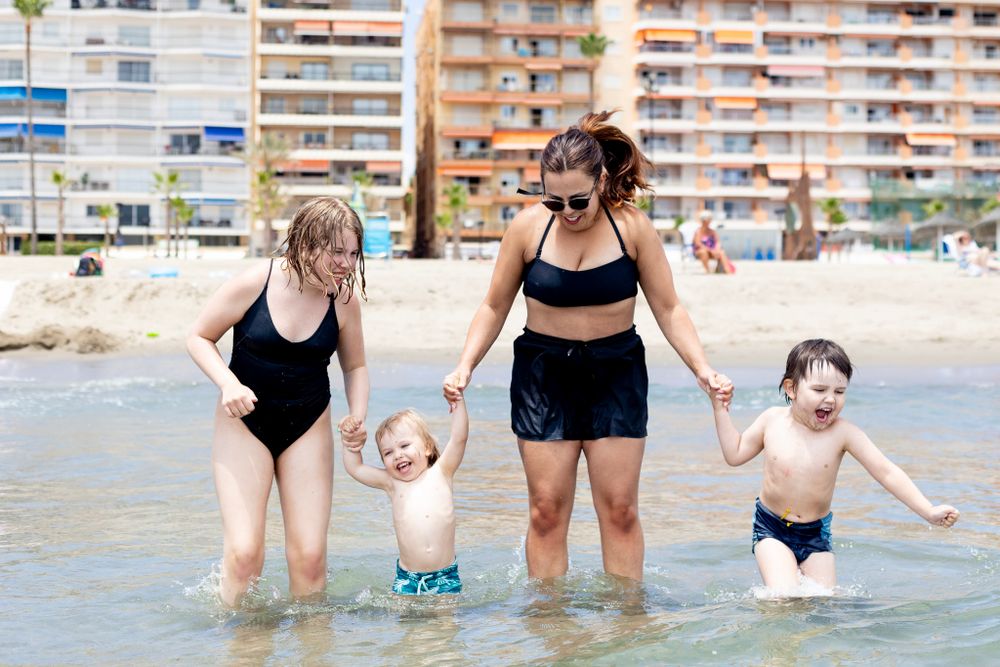 Mother jumping with her children at the beach