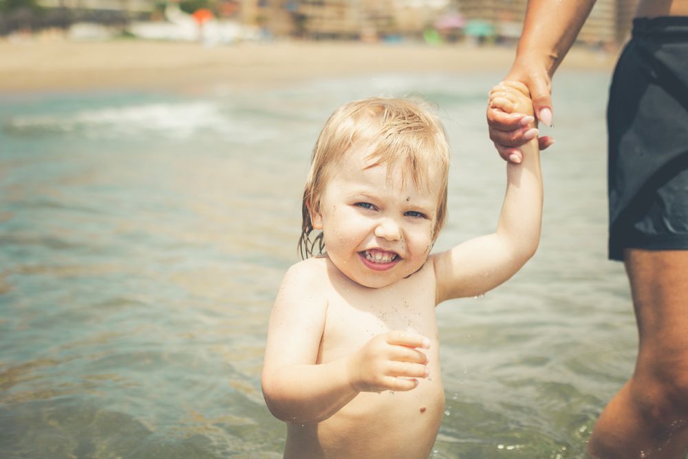 Mom holds her little boys hand at a summer family session.