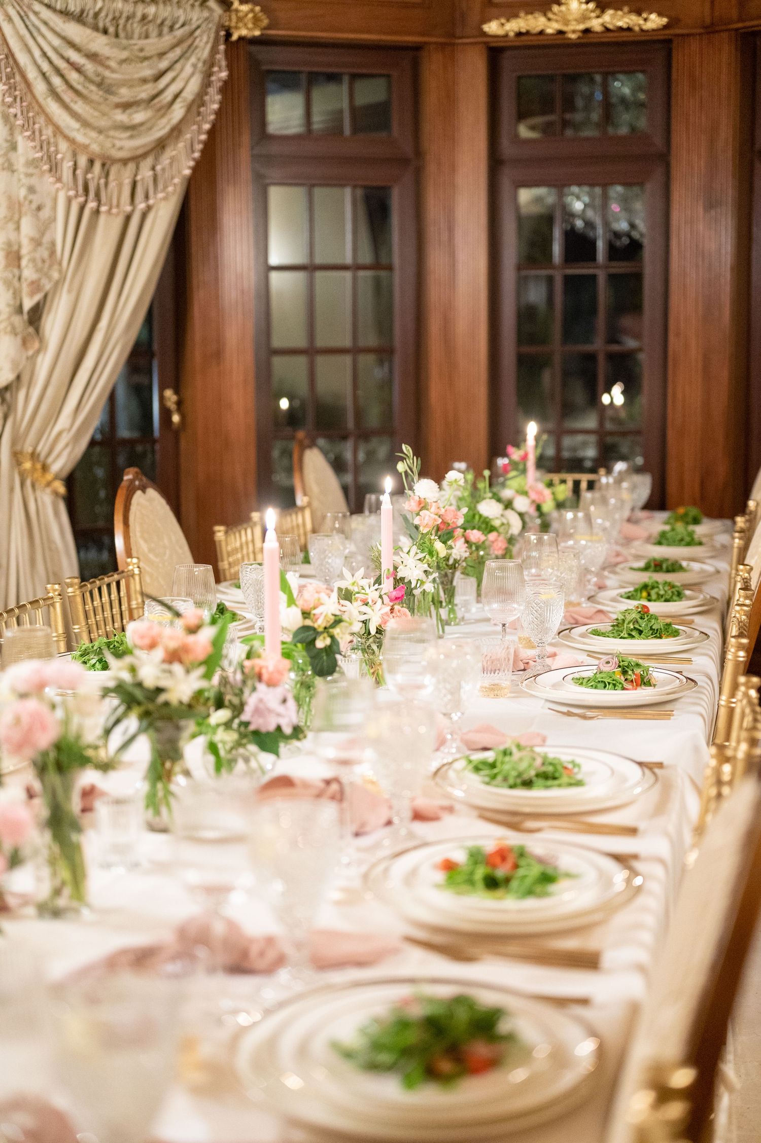 A beautifully decorated table at a rehearsal dinner, featuring plates served with fresh salad.