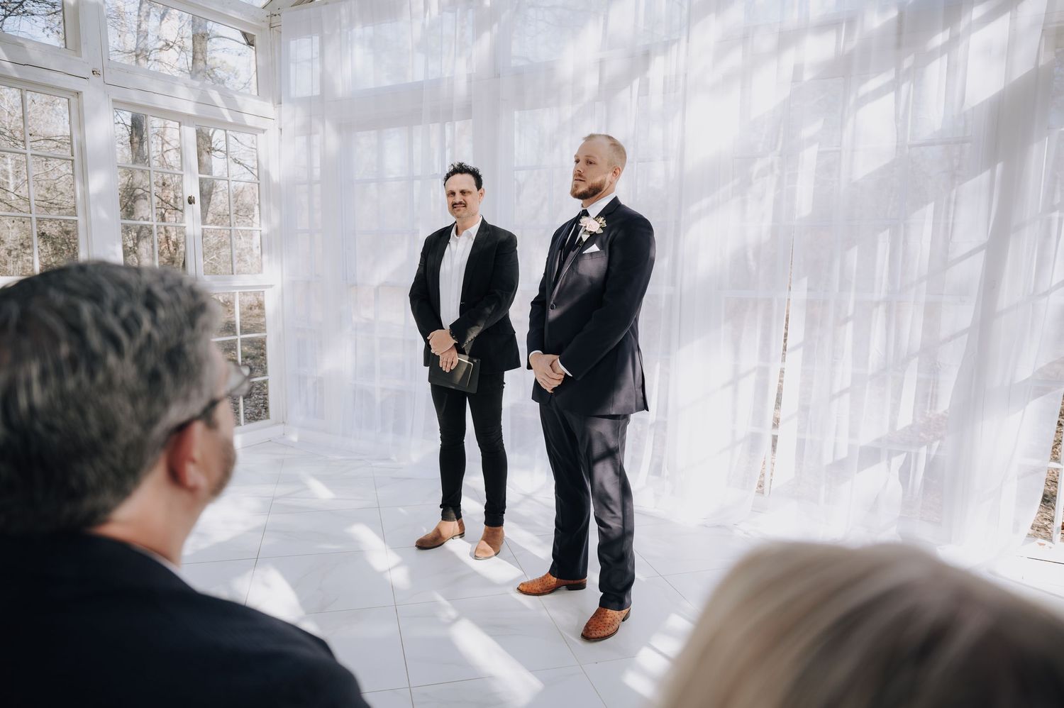 A ceremony in a glass-enclosed space with natural light streaming through windows.