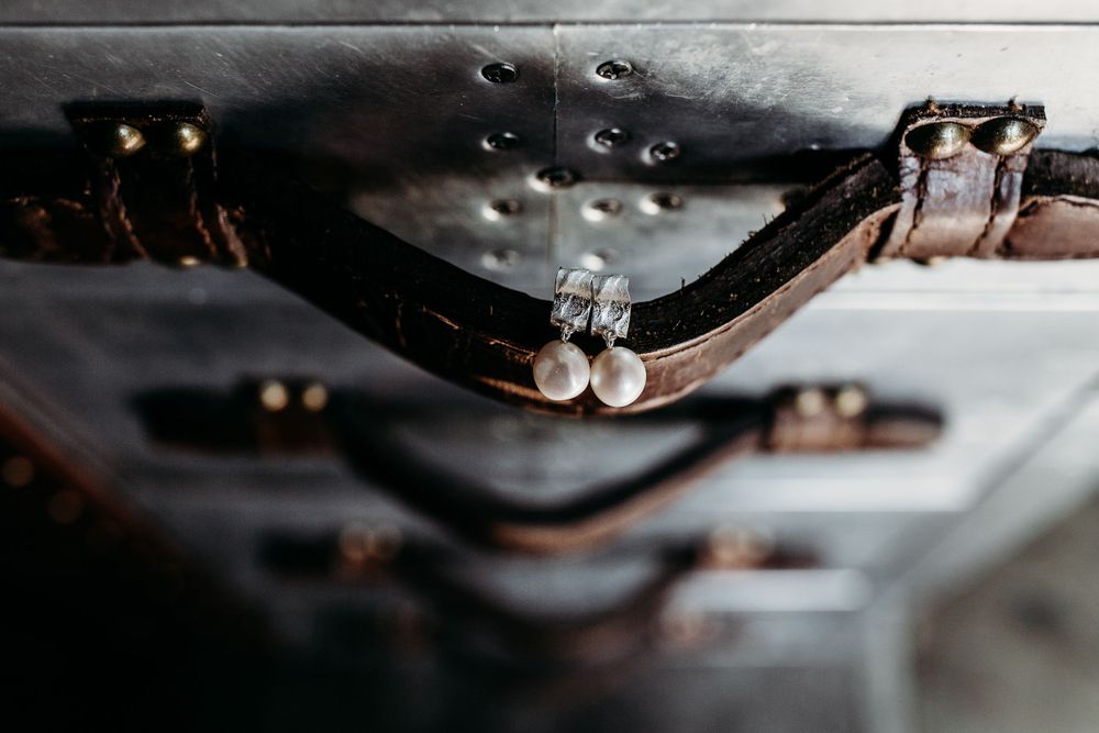 Close up of vintage leather camera straps with water droplets in moody lighting.