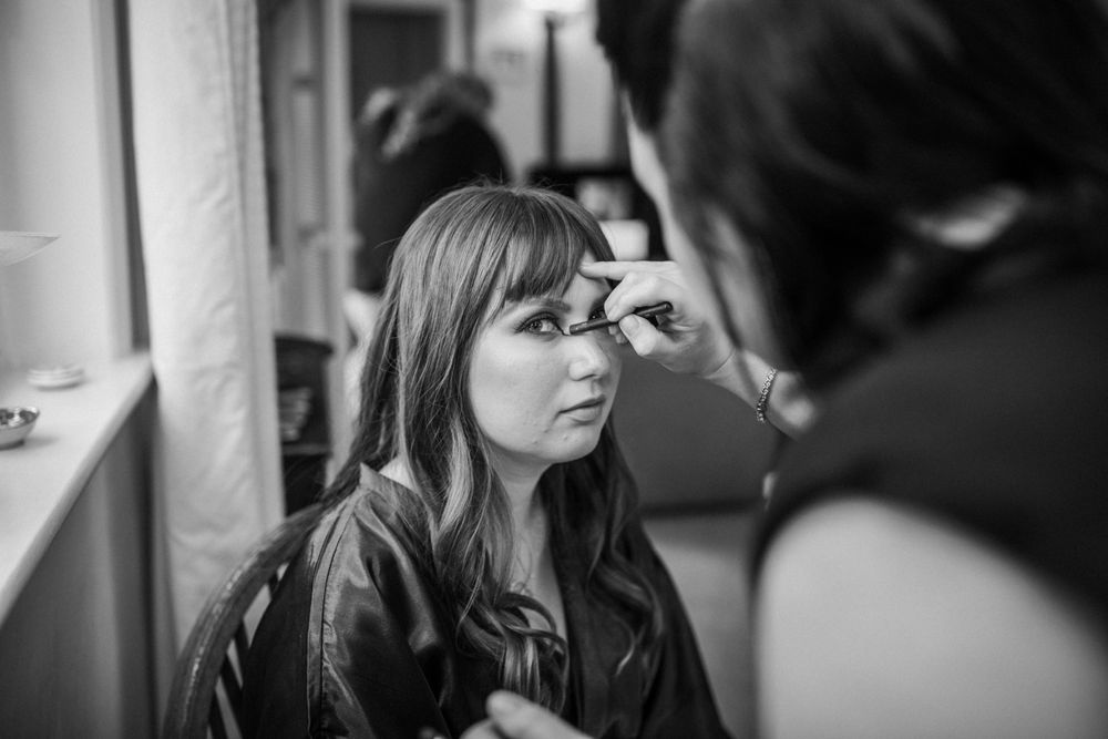 A woman having her makeup professionally applied in black and white photography.