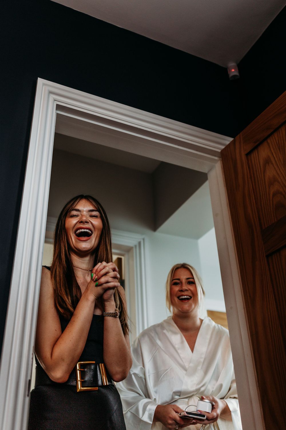 Candid moment of laughter and joy during wedding morning preparations.