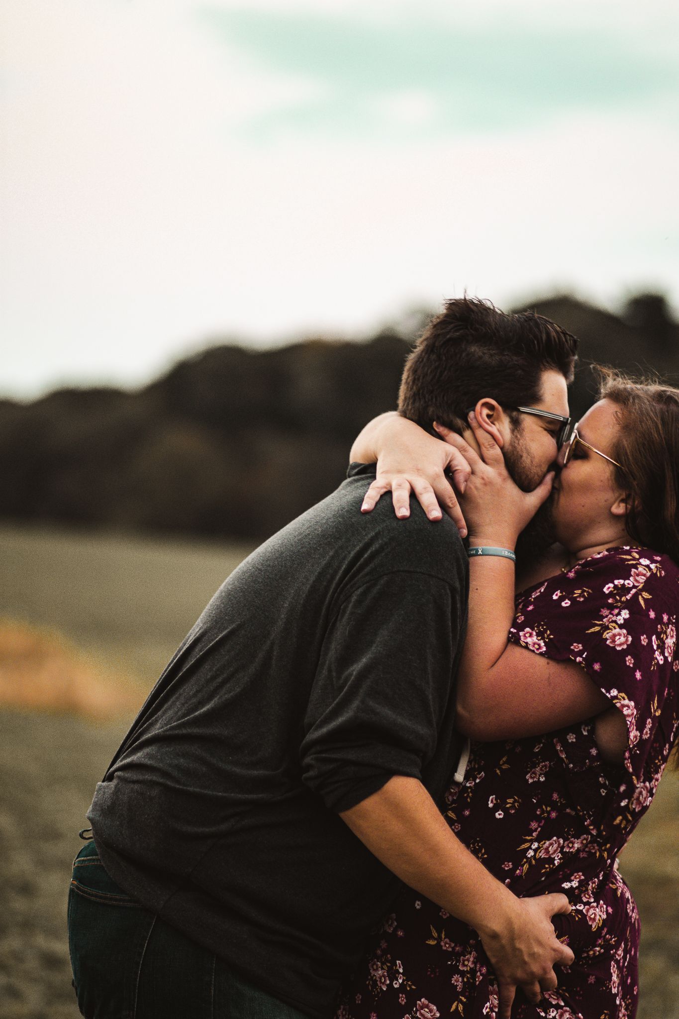 Intimate moment between couple in casual wear against natural outdoor backdrop.