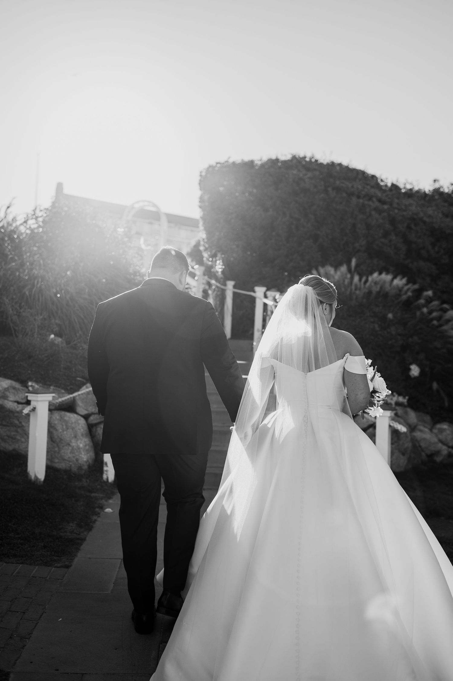 Dreamy black and white wedding photography of couple walking together outdoors.