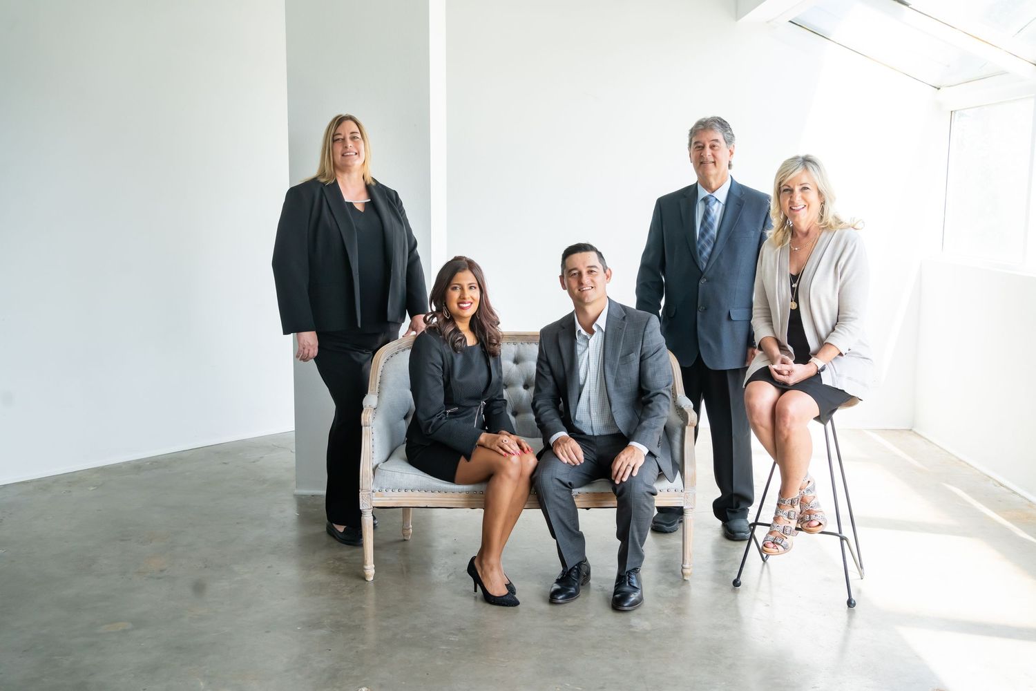 Professional business team posed together in modern minimalist office space.