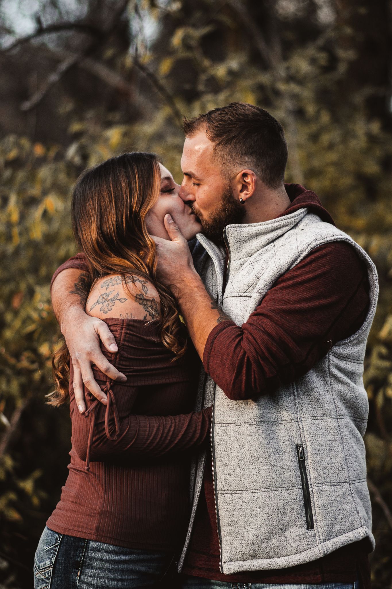 Close-up engagement portrait of couple in matching burgundy and grey outfits.