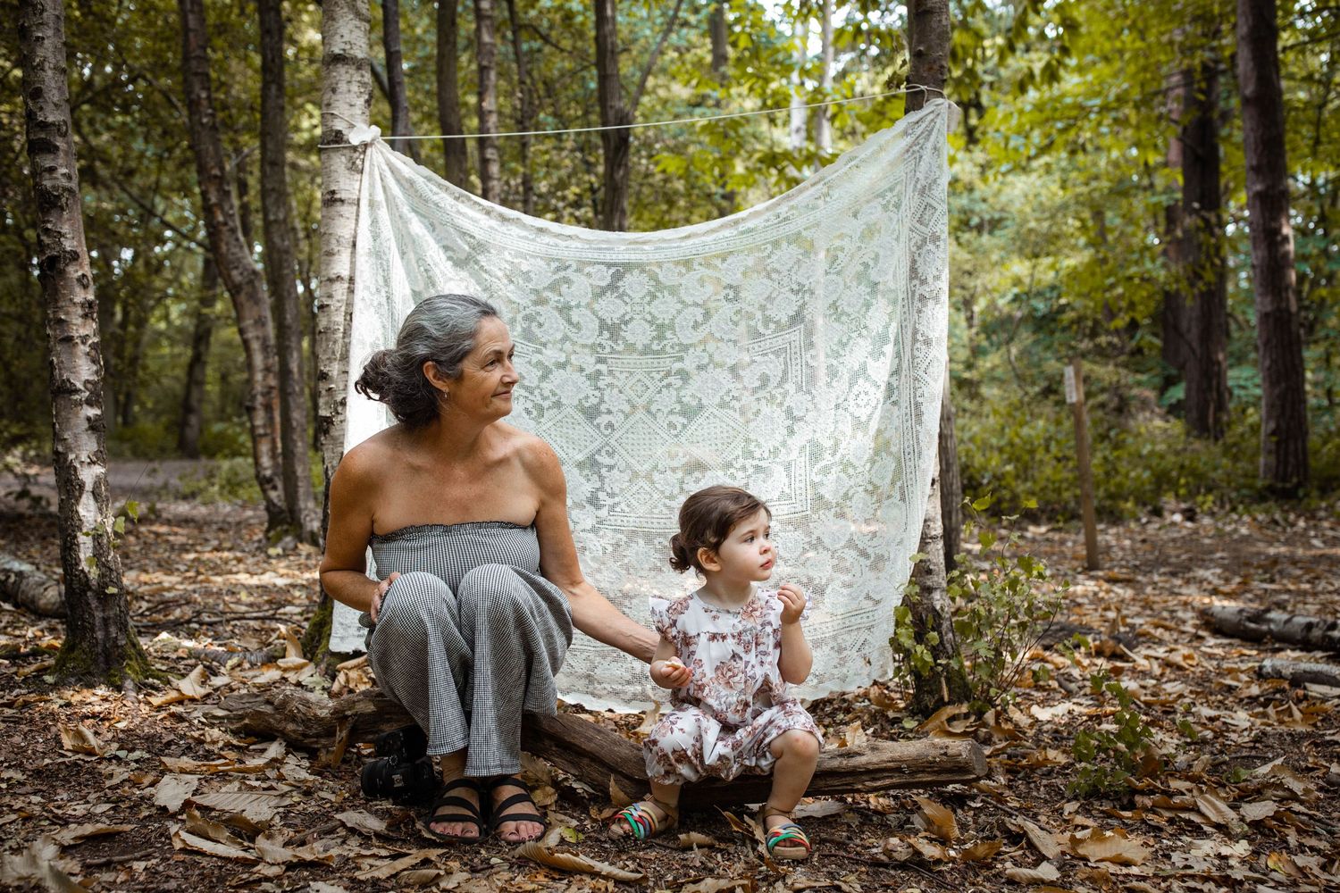 A woodland portrait session with a lace backdrop on fallen leaves.