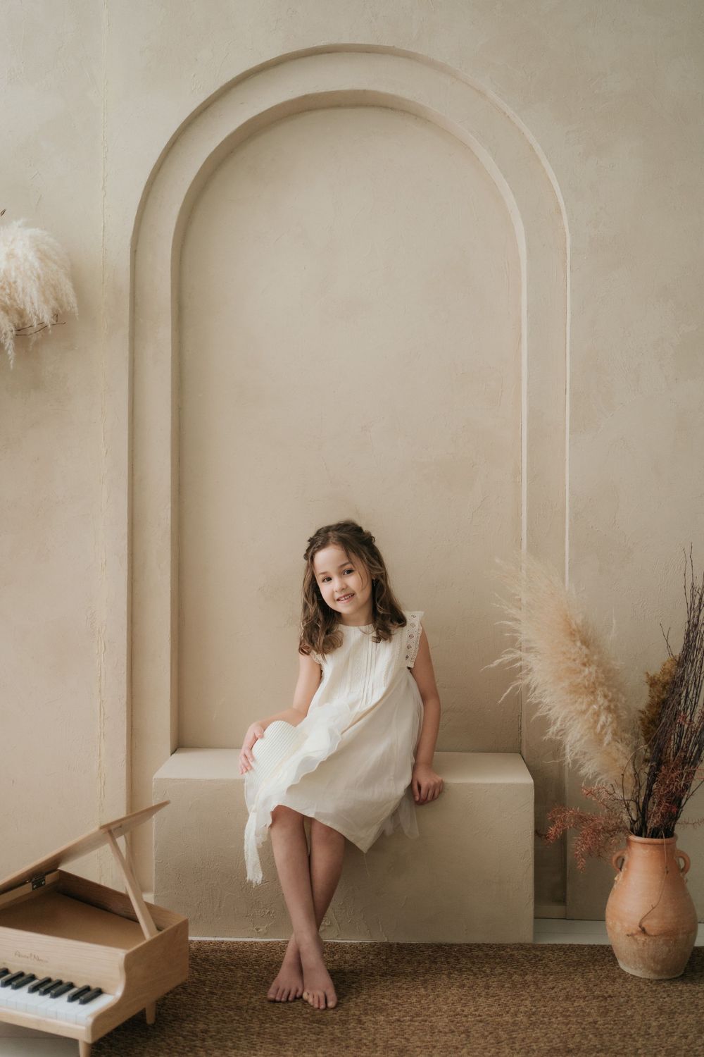 Minimalist portrait session featuring white dress against neutral archway backdrop.
