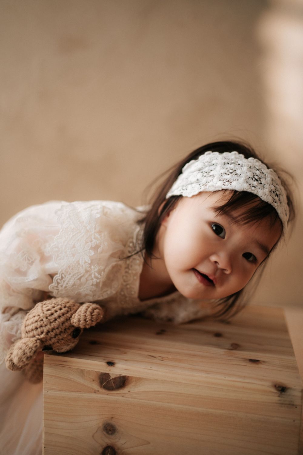 Sweet photo series of a small child peeking over a wooden surface wearing lace.