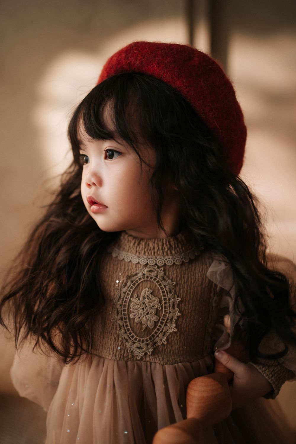 Close-up shots of a detailed porcelain doll wearing a red hat and vintage dress.