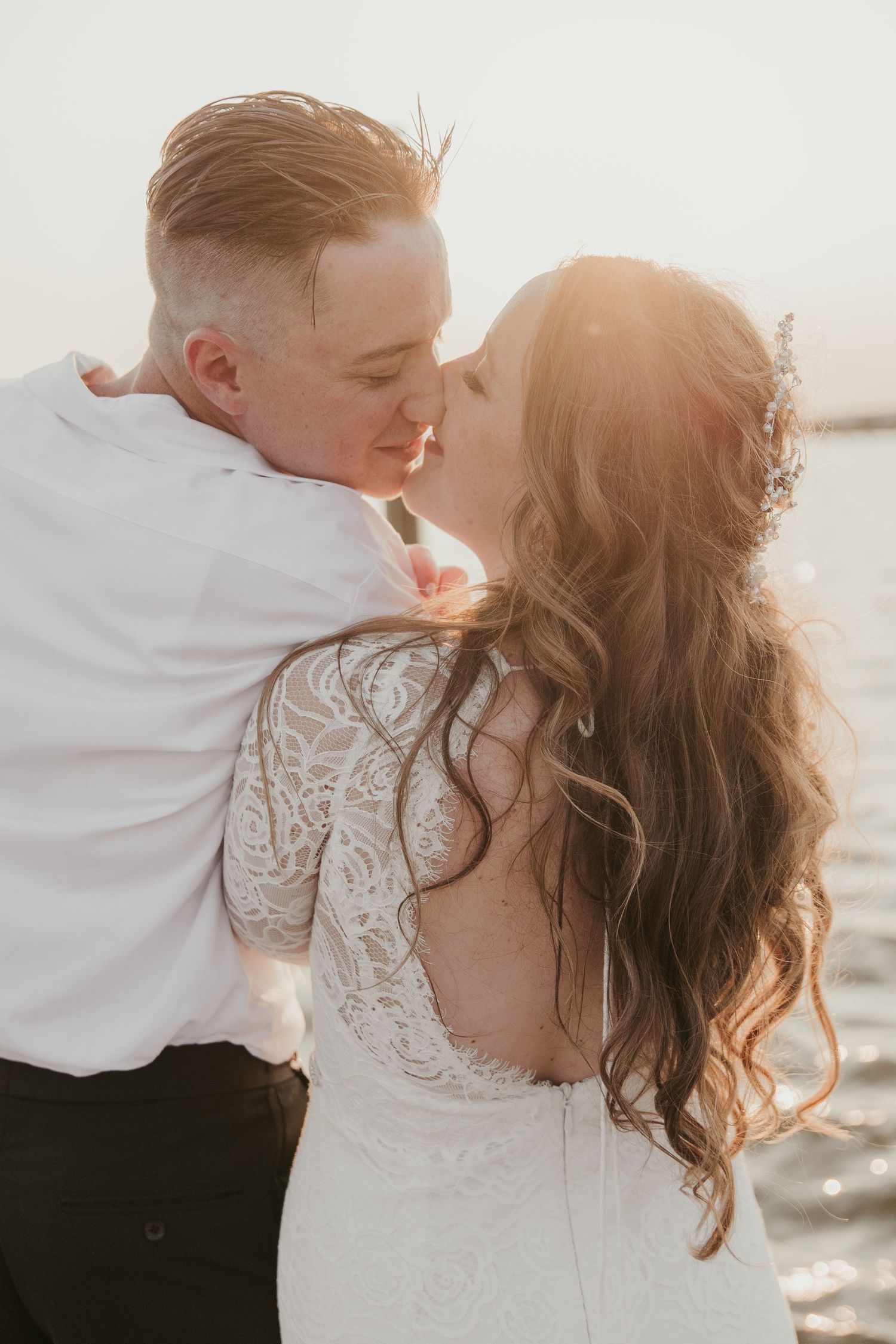 Romantic sunset wedding portrait with bride's lace dress detail.