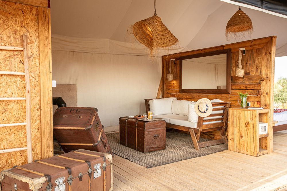 Rustic glamping interior with vintage trunks and woven pendant lights.