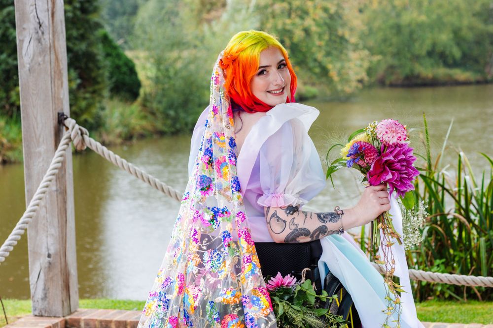 a rainbow hair femme non binary person in a rainbow pastel dress at Brookfield Barn