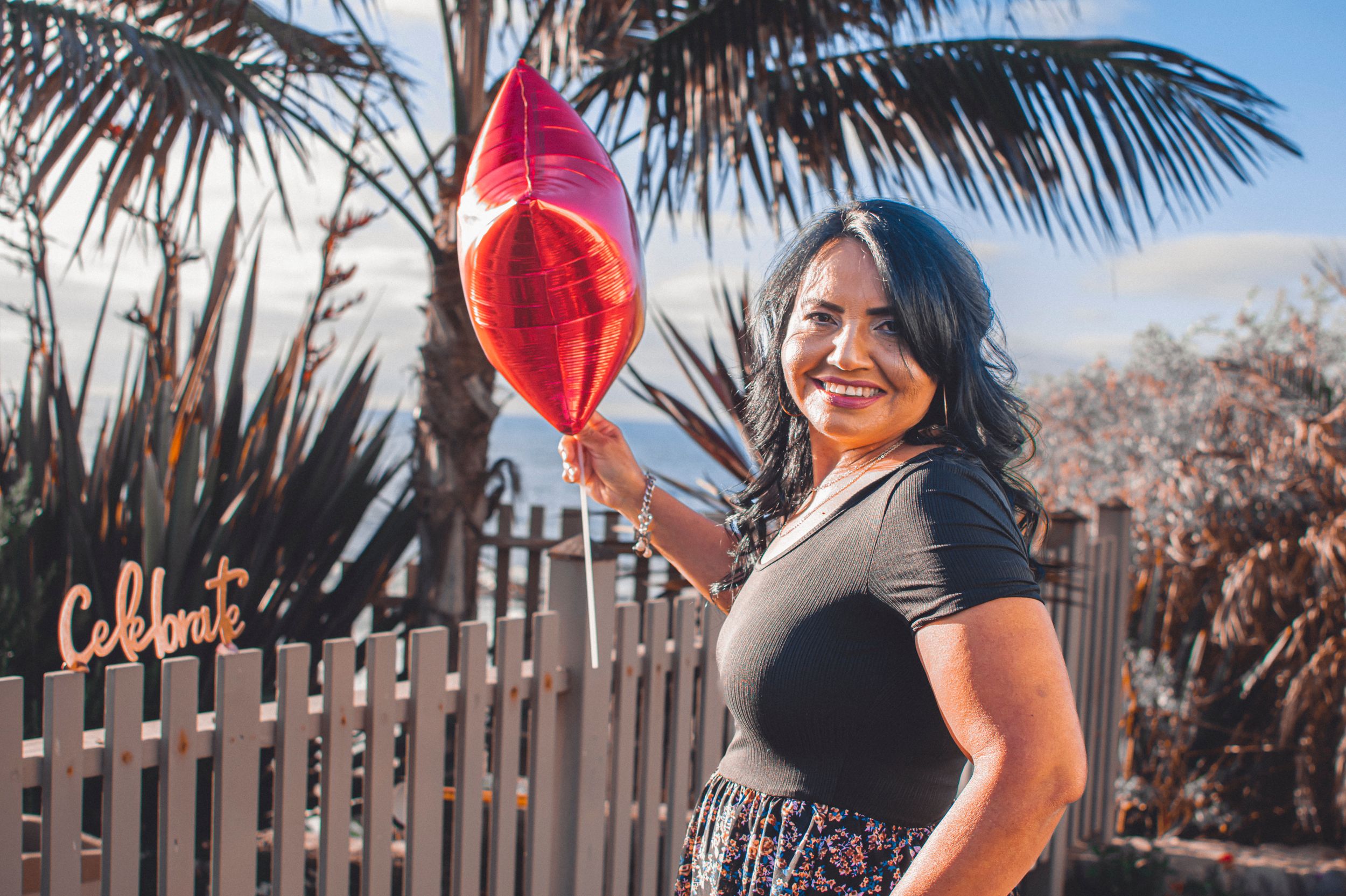 A joyful outdoor scene with palm trees and a red heart-shaped balloon.