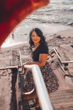 A beachside portrait session on wooden stairs with dramatic lighting and ocean views.