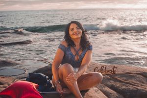 Sunset photoshoot on rocky beach featuring casual poses and ocean scenery.