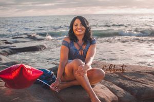 Natural light portrait session on rocky shoreline with waves crashing in background.
