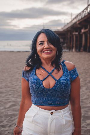 Beach fashion photography featuring blue crop top and white shorts near wooden pier.