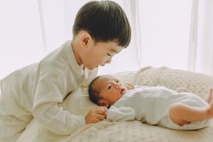 Older sibling's first moments with the newborn, lying on a cozy blanket