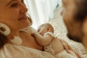 A candid family moment with a mother holding her baby, surrounded by love and laughter, in a newborn studio