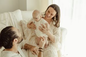A candid family moment with a mother holding her baby, as they interact with the father in a bright newborn studio