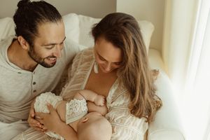 oyful parents gazing adoringly at their breastfeeding baby, in a newborn studio filled with natural light