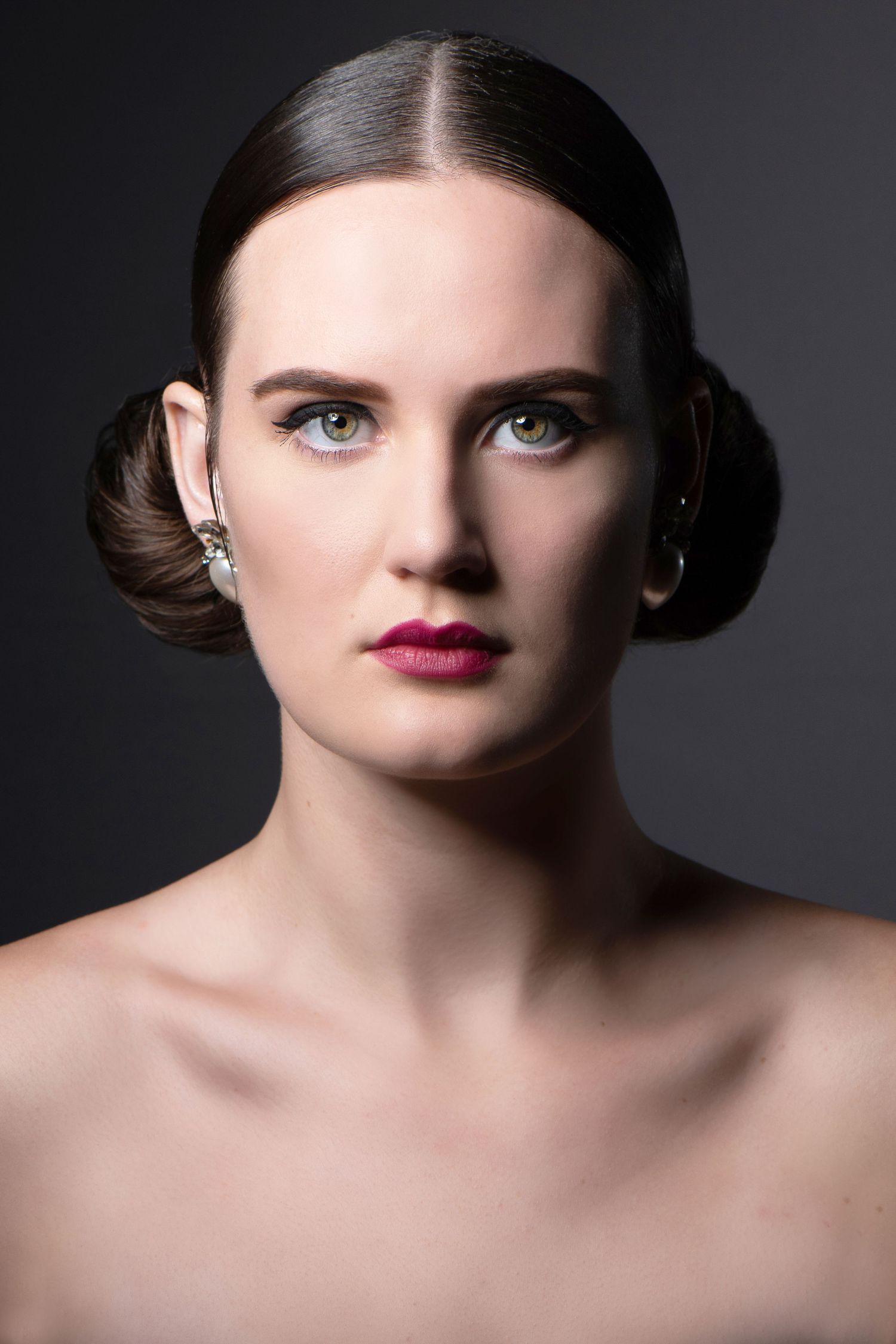 Classic beauty portrait with dramatic lighting featuring sleek updo and red lipstick.