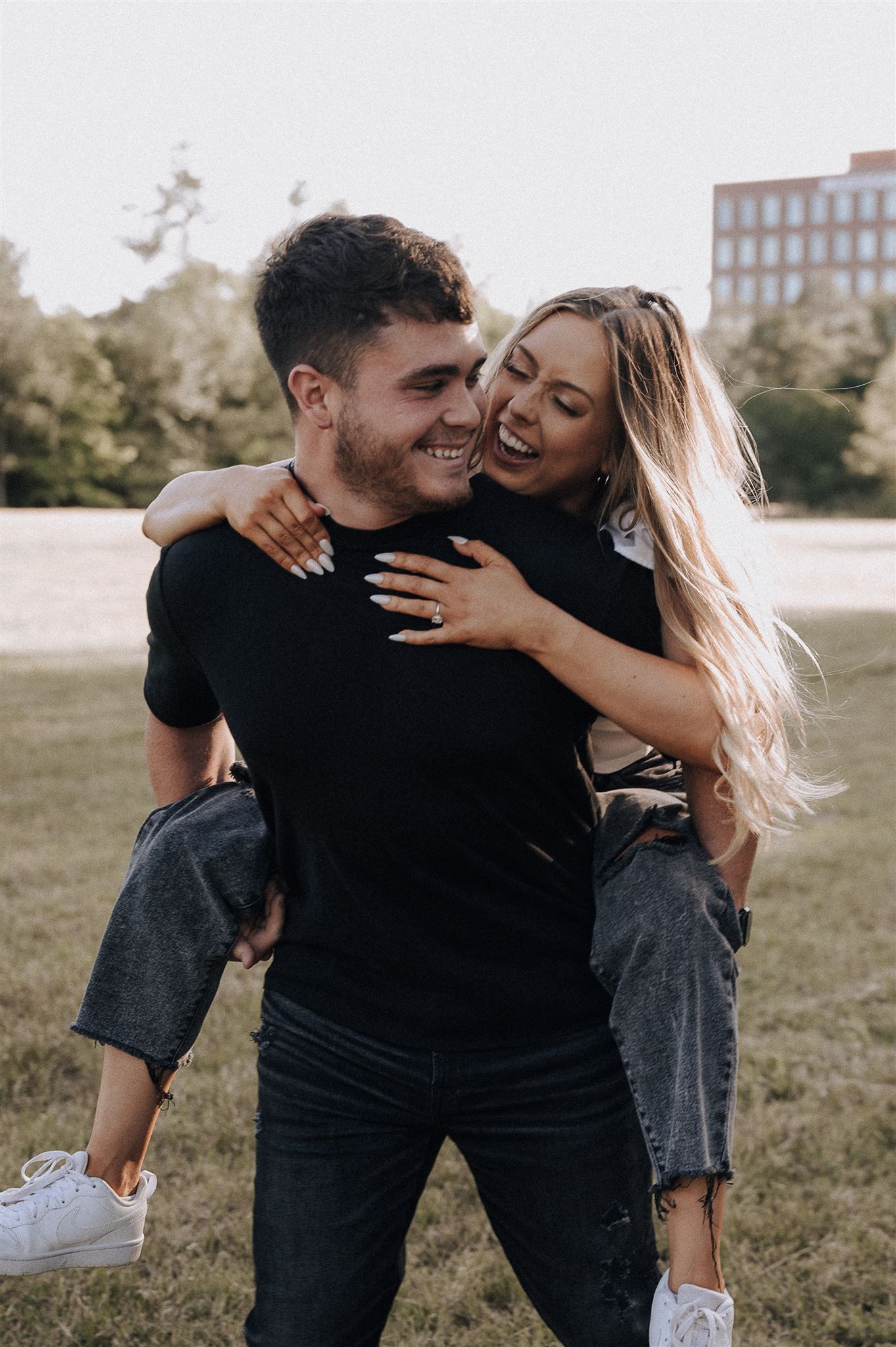Joyful couple sharing a piggyback ride moment in a sunny outdoor setting.