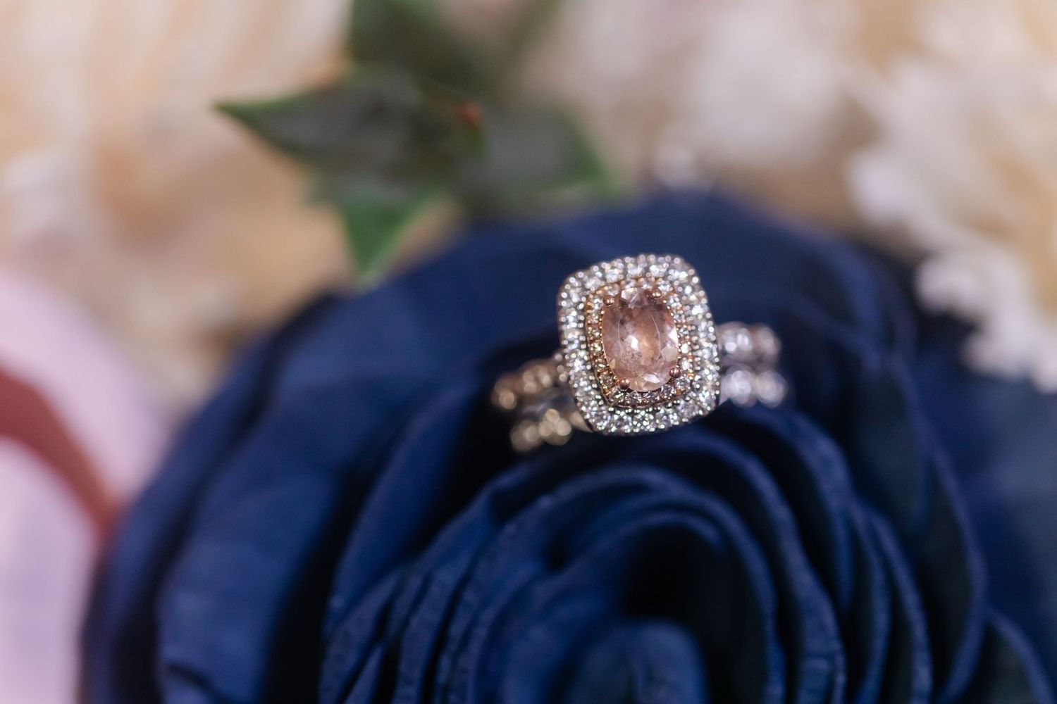 Close-up of wedding rings displayed on a navy blue fabric with sparkly details.