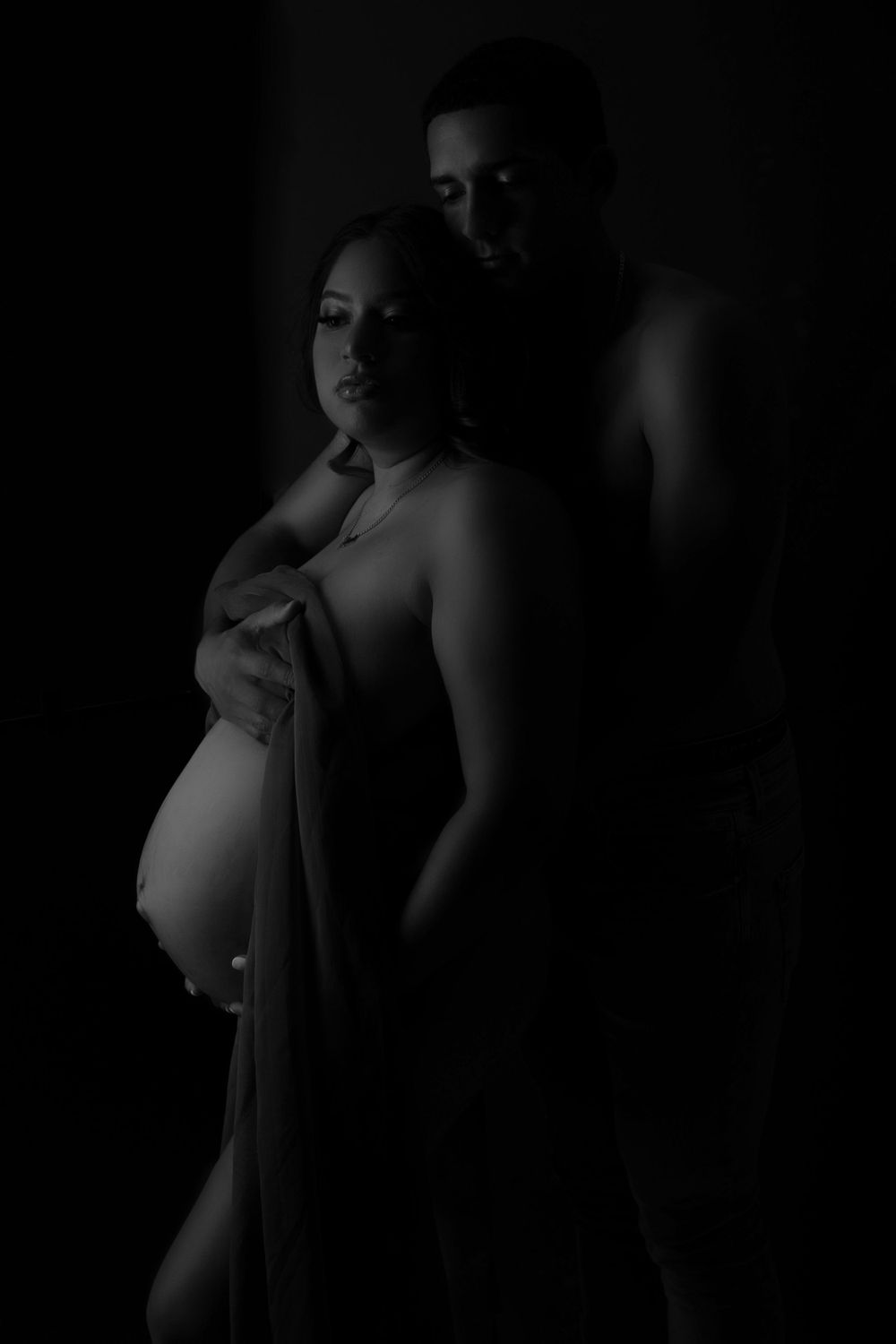 Artistic black and white maternity photo showing silhouette of expectant couple.