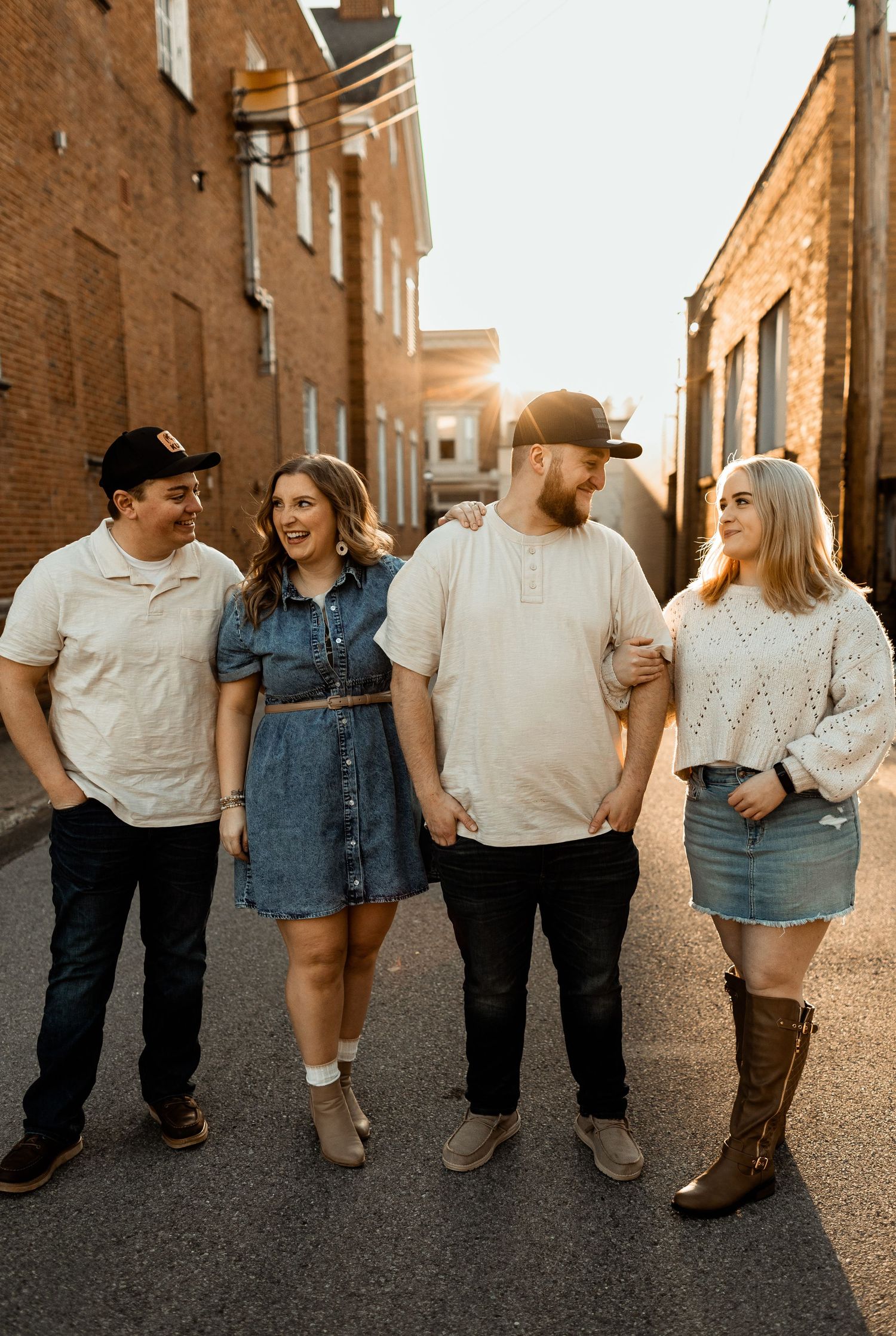Group walking and laughing together on sunset-lit street between brick buildings.