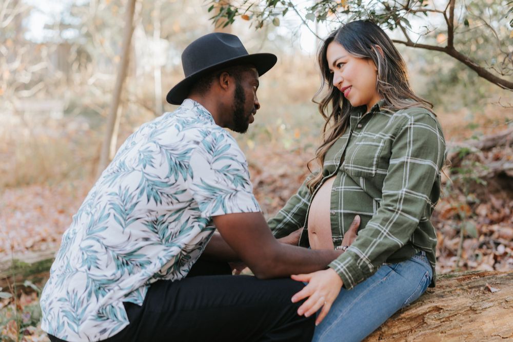 Intimate forest maternity photo with couple in casual clothing.