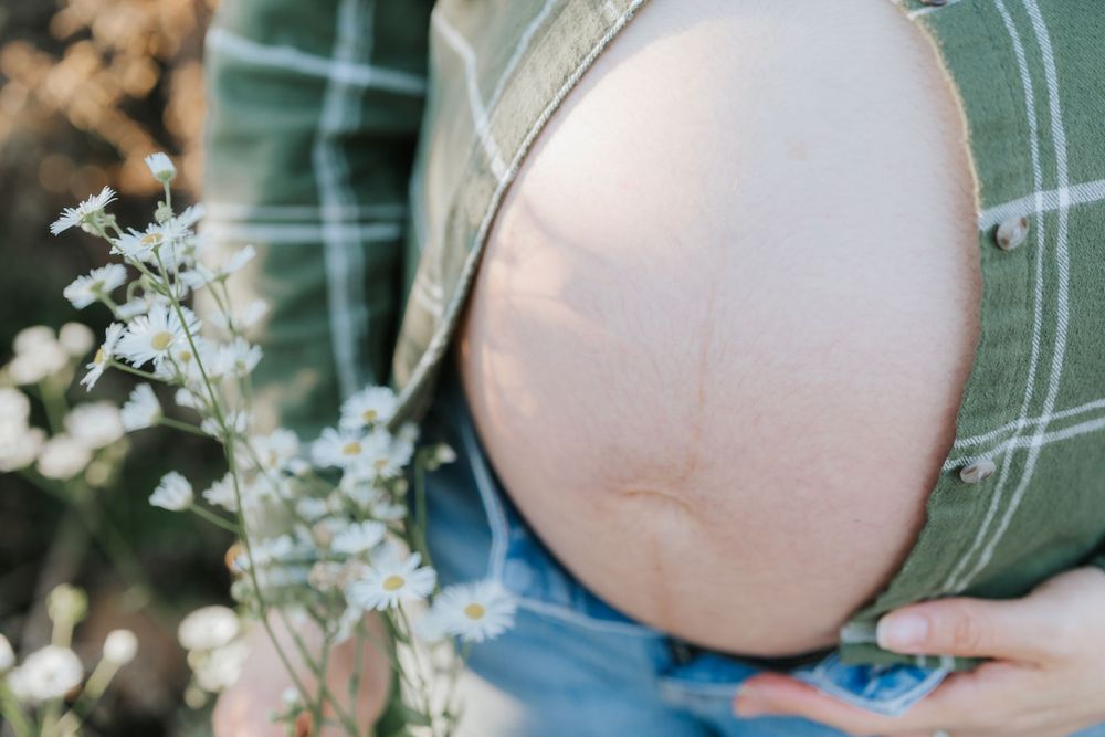 Artistic maternity photo showing pregnant belly with delicate white flowers in frame.