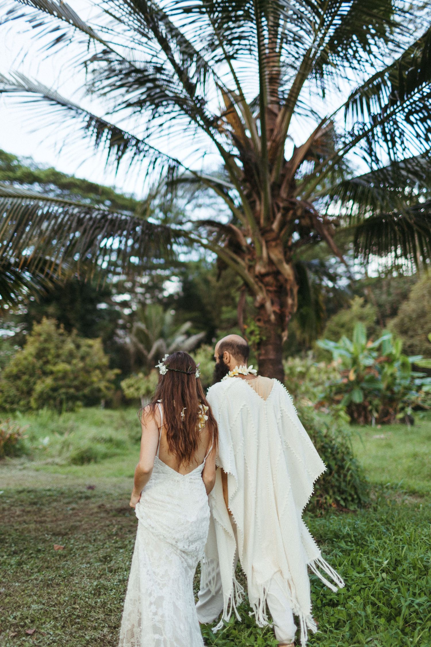 couple walks hand in hand with a coco palm in the background, during their hawaii elopement package